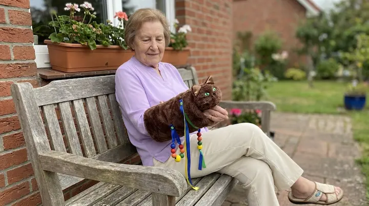 Elderly woman sitting calmly while gently moving her hands inside a soft sensory sleeve
